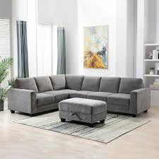 Gray sectional sofa with matching ottoman on a light rug in a well-lit room. Wall art in background.